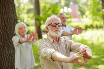 Fototapeta premium Senior man doing chi kung meditation exercise outdoors