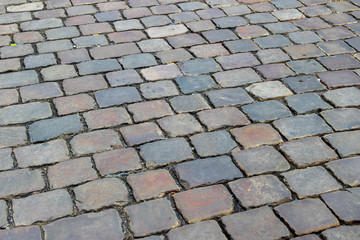 An old stoneblock pavement cobbled with rectangular natural stone blocks. Photo in perspective with selective focus