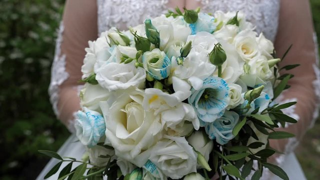 The bride in a white dress holds in her hands the flowers. Shooting with a 3-axis motorized gimbal stabilizer.