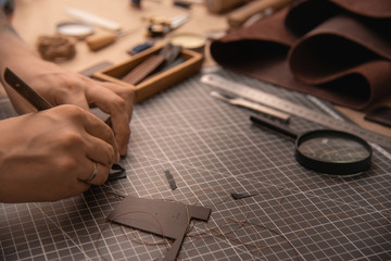 Working process in the leather workshop. Man's hands holding crafting tool