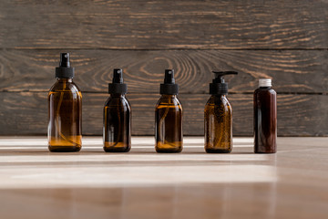 Cosmetic dark amber glass bottles on wooden background. Closeup, copyspace. Beauty blogging, salon treatment concept, miinmalism packaging 