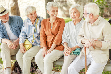 Cheerful senior people sitting on bench and chatting