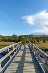 Fototapeta na wymiar Holzbrücke in Norwegen im Herbst mit Fluss und Wolken
