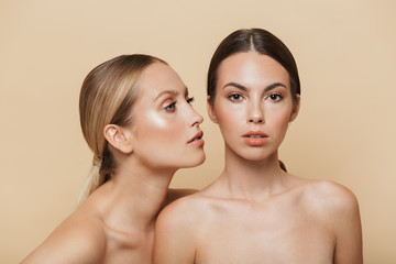 Women posing naked isolated over beige wall background.