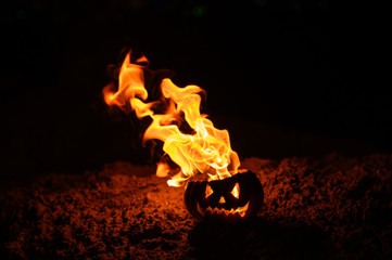 Tongues of flame in a pumpkin. jack-o-lantern on fire on a black background. Halloween symbol on the ground. Trick or treat. Close up.