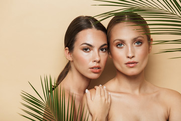 Serious women posing naked with green nature leaf plant.