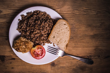 cooked buckwheat, meat cutlet, tomato and bread in a white plate with a fork. food background,