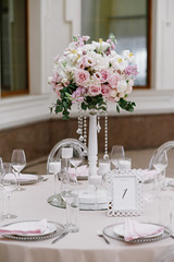 Wedding flowers on a tall white wooden stand decorate the festive table