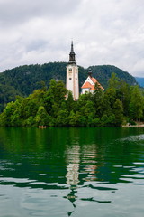 View of the island on Lake Bled with the pilgrimage church of the Assumption of Mary with reflection on a cloudy day.