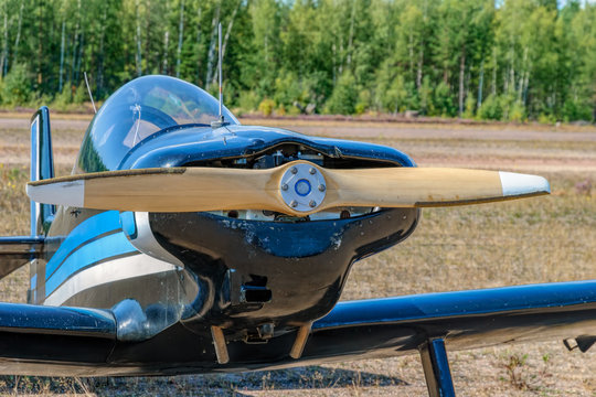 Frontal close-up view of engine and propeller of single-engined light airplane at sunny day.