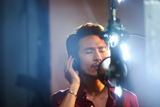 young asian musician recording songs in studio
