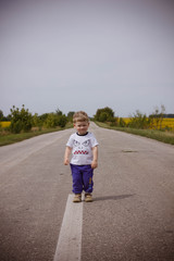 little boy walks alone in the middle of the road