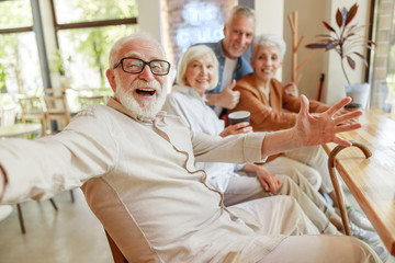 Cheerful old people making selfie in cafe - obrazy, fototapety, plakaty