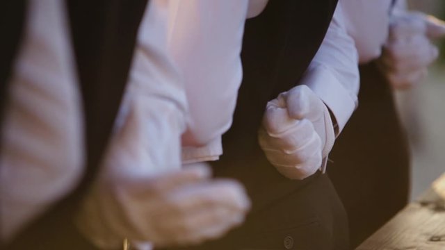 Row of waiters with white gloves and tuxedo serving the high class people