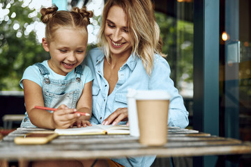 Happy mother and daughter drawing in notebook stock photo