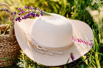 A large round female hat made of natural materials in rustic style. The hat lies on the grass