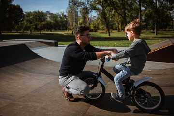 Fototapeta premium Father teaches son the basics of driving bicycle