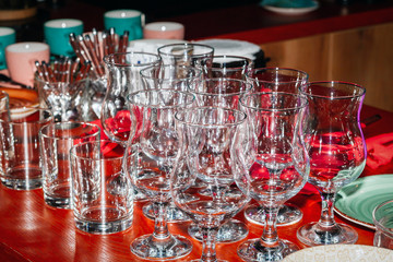 Rows of glass glasses on a red counter, a low key image.