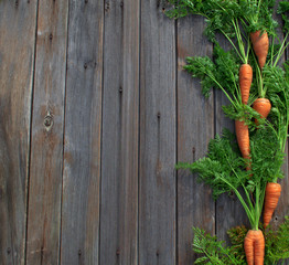 Orange sweet juicy carrots lie on old dark boards