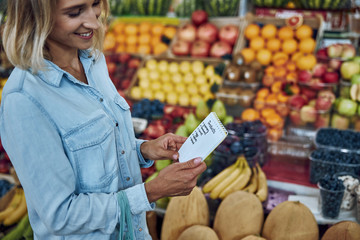 Woman buying food according to her shopping list stock photo