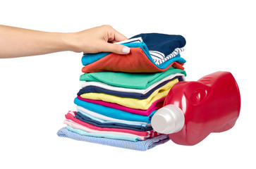 Hand with stack of clothes and detergent bottle, fresh laundry textile.