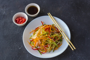 Asian style vegan salad bowl with vegetable mix on a dark background top view.