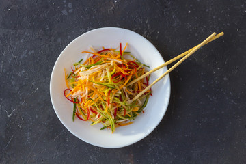 Asian style vegan salad bowl with vegetable mix on a dark background top view.