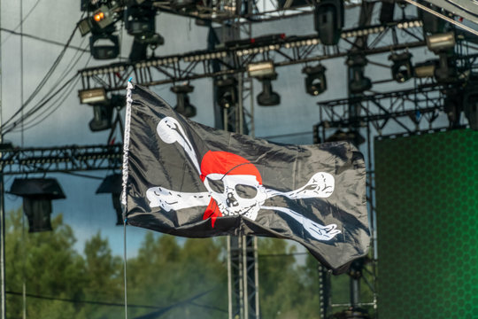 jolly Roger. Pirate flag close-up on the background of lighting equipment. Symbol of pirates. Pirate flag at the concert