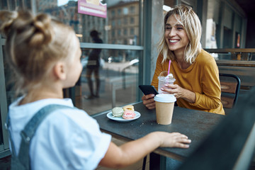 Woman with smartphone smiling to daughter stock photo