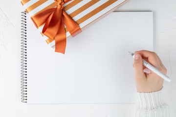 hands hold an blank notebook among gift box. Flat lay.