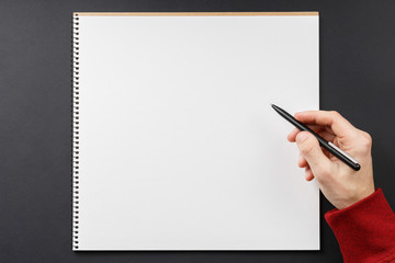 notebook with black pen in hands on black background
