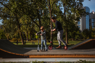 Little boy riding a push scooter with his dad