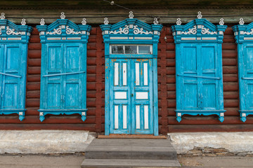 Window with the wooden carved architrave in the old wooden house in the old Russian town. Irkutsk