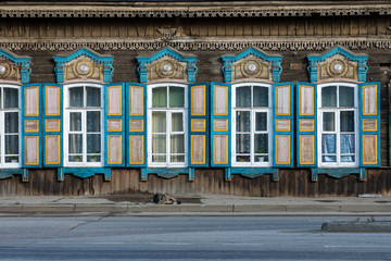 Window with the wooden carved architrave in the old wooden house in the old Russian town. Irkutsk