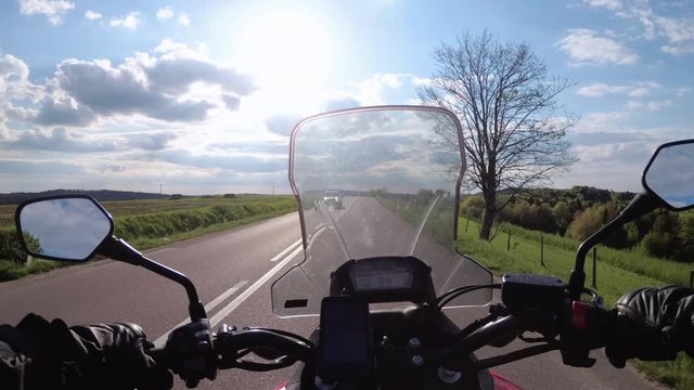 Motorcyclist Riding on the Beautiful Empty Road near Green Fields and Hills. First-person view