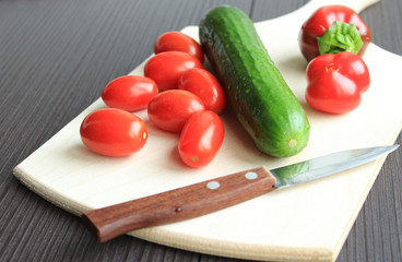  Fresh vegetables with a knife lie on a wooden board.