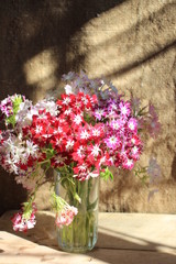  A bouquet of flowers in a glass cup stands on a wooden table.