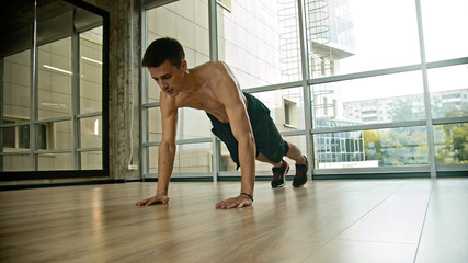 Fototapeta na wymiar An athletic half naked man doing push-ups in the studio