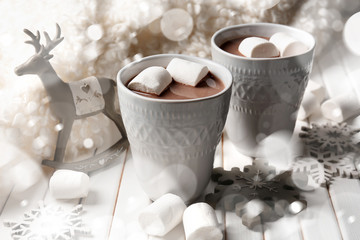 Cups of hot cocoa with marshmallows and Christmas decorations on wooden table