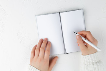 notebook with empty sheet on a white background with pen in hands