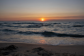 Red-orange sunset on the sea with a prominent sailing yacht on the horizon.  Bright colors of sea sunset.
