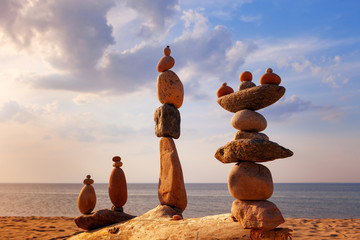 Several Rock zen pyramids of colorful pebbles standing on the beach, on the background of the sea. Concept of balance, harmony and meditation.