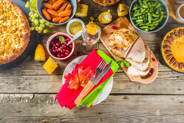 Thanksgiving family dinner setting concept. Traditional Thanksgiving day food  with turkey, green beans and mashed potatoes, stuffing, pumpkin, apple and pecan pies, rustic wooden table