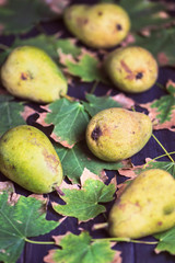 pear and autumn tree leaves on dark wooden background