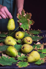 pear and autumn tree leaves on dark wooden background