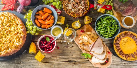 Thanksgiving family dinner setting concept. Traditional Thanksgiving day food  with turkey, green beans and mashed potatoes, stuffing, pumpkin, apple and pecan pies, rustic wooden table