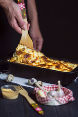 hand cook lasagna with meat and cheese, with sauce, in a baking dish