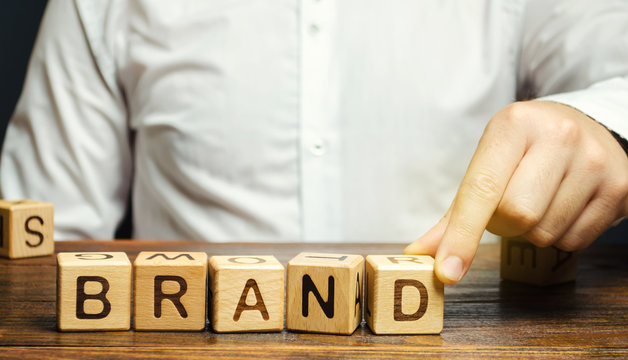 Businessman puts wooden blocks with the word Brand. Business, marketing, and advertising. Name, term, design, symbol that identifies one seller's good or service.