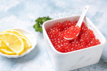 Bowl with red caviar on table