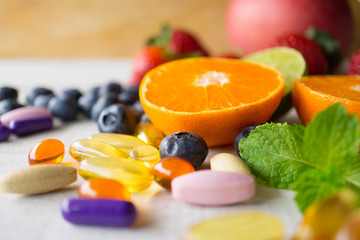 Colorful pills and capsules with fresh fruits.Vitamins and supplement from fruits concept.